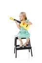 Mini muso. Studio shot of a cute little girl playing with her toy guitar against a white background. Royalty Free Stock Photo