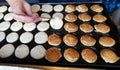 Mini pancakes frying on iron pan. Flipping half cooked pancakes around. Photographed in Tallinn, Estonia.