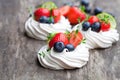 Mini Pavlova meringue cakes with berries and lime on rustic woo