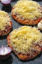 Mini pizzas or small pellets covered with cheese on black glance surface close-up macro Royalty Free Stock Photo