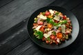 Mini potato gnocchi tricolour with tomato, spinach, Seasonal salad leaves and parmesan cheese on black plate