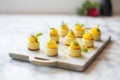 mini raw mango cheesecakes in rows on tray