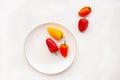 Mini red and orange sweet peppers on a white plate on a white background. horizontal Royalty Free Stock Photo