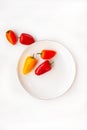 Mini red and orange sweet peppers on a white plate on a white background Royalty Free Stock Photo