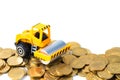 Mini Road roller machine with pile of gold coin, isolated on white background with copy space, business finance and banking indus Royalty Free Stock Photo