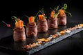 Mini roast beef rolls with vegetables, on a black slate plate, on a black background. Fusion food concept, low key, copy Royalty Free Stock Photo