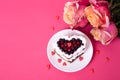 Heart shaped cake decorated with red currant on pink back