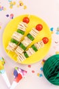 Mini Shaped Sandwich Kabobs with cheese, ham, cucumber, cherry tomato and wholemeal bread over yellow plate on pink background