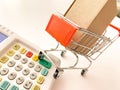 Mini shopping cart with a box and calculator isolated on a pink surface Royalty Free Stock Photo