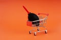 Mini shopping cart carrying a dust blower for camera and lens cleaning. Close-up shot, orange background