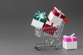 Mini shopping cart full of colorful gift boxes with ribbons.