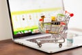 Mini shopping cart full of different homeopathic remedies on laptop background. Royalty Free Stock Photo