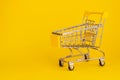 Mini shopping cart isolated on yellow background. Empty supermarket trolley. Buying online concept. Royalty Free Stock Photo