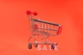 Mini shopping cart with word SALE on a red background. The concept of shopping in stores and online Royalty Free Stock Photo