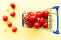 Mini shopping grocery cart full of fresh cherries. Fresh berries on yellow background. Healthy, summer food concept. Top Royalty Free Stock Photo