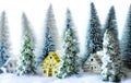 Mini snowy Christmas trees with houses in the forest. Bokeh lights background Royalty Free Stock Photo