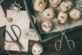 Mini stollen with sugar icing on a wooden tray, paper bags, scissors and gift ribbon on dark wood