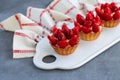 Mini strawberry tartlets on ceramic board with linen napkin on stone table