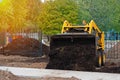 Mini tractor pours the soil out of the bucket, yellow excavator at work Royalty Free Stock Photo