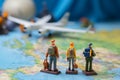 Mini travelers, male and female, with backpacks, gather around a world map and airplane model Royalty Free Stock Photo