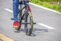 Mini trick stunt bike with camouflage fat tires and pegs being ridden by guy in red tennis shoes and blue jeans on paved surface