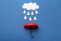 Mini umbrella and paper raindrop cloud on blue background, flat lay Royalty Free Stock Photo