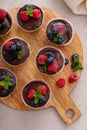 Mini vanilla cheesecakes cooked in a muffin pan with chocolate ganache served with fresh berries