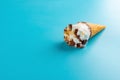 Mini Vanilla flavor ice cream cone starts melting on blue Royalty Free Stock Photo