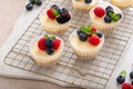 Mini vanilla cheesecakes cooked in a muffin pan served with fresh berries