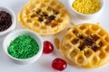 Mini waffles, cake sprinkles and cherries on white background