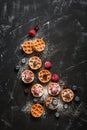 Mini waffles with raspberries and blueberries on a black stone background, flat lay. Belgian traditional waffles with berries. Top