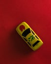 A mini yellow colour toy car on a red background