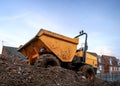 Mini yellow dumper truck with roll bar and orange green flashing lights on top tipper front bucket parked on construction mound