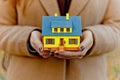 Mini yellow house model in woman hands for mortgage offers and money saving with the buying a property or interior design Royalty Free Stock Photo