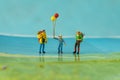 Miniature backpackers with happy man holding ballons standing on