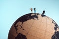Miniature backpackers standing on top of the earth globe