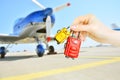 Miniature baggage in female hands on blurred background with plane airscrew.