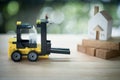 Miniature banker sit on yellow forklift go to move home to another location