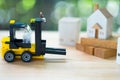 Miniature banker sit on yellow forklift go to move home to another location