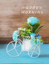 A miniature bicycle with bouquet of light blue roses and message `good morning` on blue background Royalty Free Stock Photo