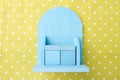 Miniature blue cupboard on dotted yellow background.