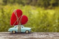 Miniature blue toy car carrying a heart on the blurry natural gr