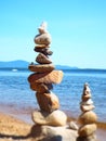 Miniature blurred effect of two rock tower cairns on sandy beach and lake