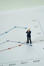 Miniature brave businessman standing on graph as business yearly