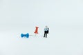 Miniature business concept - a businessman standing beside red and blue thumbtack / push pin with white background