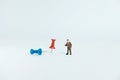 Miniature business concept - a businessman standing beside red and blue thumbtack / push pin with white background