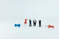 Miniature business concept - group of businessman standing beside red and blue thumbtack push pin with white background