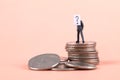 Miniature business doll standing on top of the coin with questions