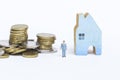 Miniature business man with stack of coins and wooden blue house isolate on white background Royalty Free Stock Photo