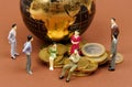 Miniature business people stand near a globe and coins. Royalty Free Stock Photo